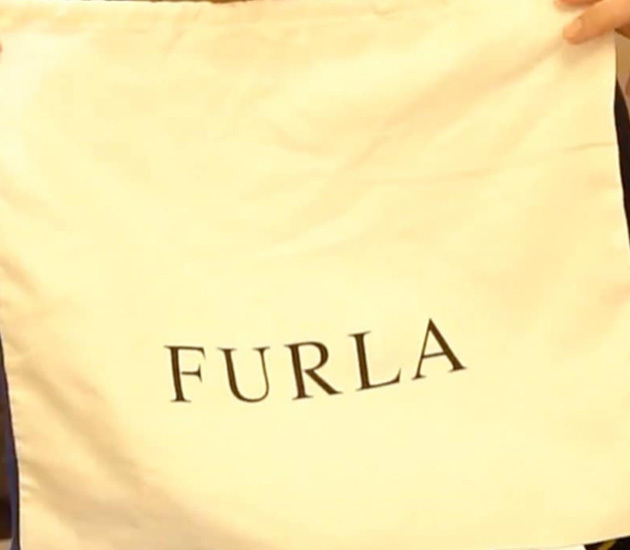 Zoom sur le sac anti poussieres de Furla avec inscription de la marque en noire devant